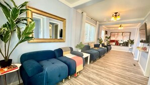 Una sala moderna con un sofá azul, un espejo grande y suelo de madera.