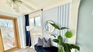 Una sala moderna con un sofá azul, una planta grande en maceta y un espejo decorativo en la pared.
