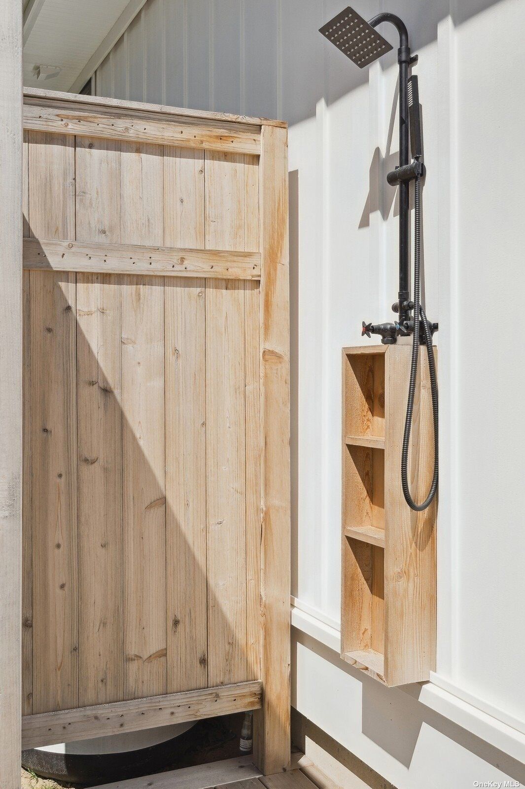 A wooden door with a built-in showerhead and a small shelf.