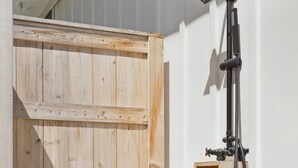 Una puerta de madera con ducha empotrada y un estante pequeño.