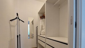 Un dressing accessible sans porte, doté d’étagères ouvertes, d’un miroir et d’un portant à vêtements.