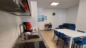 Une cuisine compacte équipée d’un évier, d’une machine à café et d’un coin repas avec une table et des chaises.