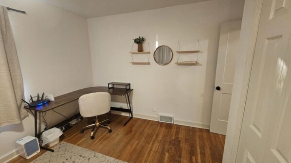 Quarto com escrivaninha, cadeira e duas prateleiras fixadas na parede com plantas.