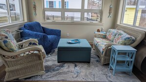A cozy room with a blue sofa, a wicker chair, and a matching ottoman. - Walk or Bike to Moody Beach (Wells)
