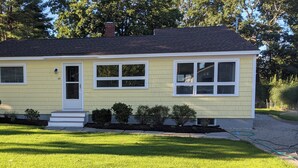A single-story house with a front door, two windows on the first floor, and a small porch with steps. - Walk or Bike to Moody Beach (Wells)