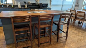 A kitchen with a wooden island, bar stools, and modern appliances. - Walk or Bike to Moody Beach (Wells)