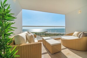Ein Balkon mit Korbmöbeln, Meerblick und einer Pflanze.