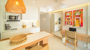 Una cocina moderna con comedor, que incluye una mesa de madera, sillas de mimbre y una lámpara colgante.