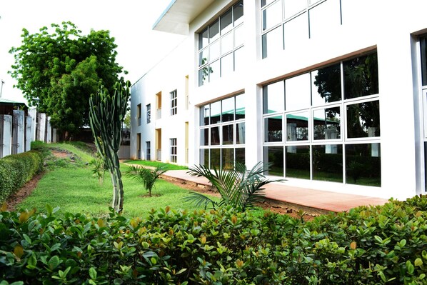A modern building with large windows and a well-maintained garden. - AUN Hotel Conference Centre and SPA (Yola)