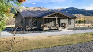 A single-story house with a porch, a covered outdoor seating area, and a view of a hilly landscape. - Welcome Hunters! Next to Garrity Mtn Wildlife Area (Anaconda)