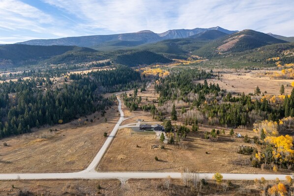 A rural landscape with a large open field, a road, and a building with a dark roof. - Welcome Hunters! The Aspens are Changing Colors (Anaconda)
