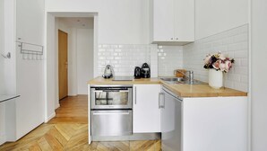 A modern kitchen with white cabinetry, a stainless steel oven, and a coffee maker on the countertop. - Authentic Apartment - 1br/2p - Palais Garnier (Paris)