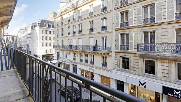 Un edificio de varios pisos con balcones y locales comerciales, incluyendo señalización visible de 'EGERIE' y 'MARINA'.