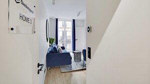 Una sala de estar moderna con un sofá azul, una mesita redonda y un ventanal con cortinas azules.