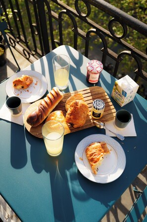 A table with food items including bread, a hot dog, and a slice of pizza, along with drinks and condiments. - Luxery 4Bedroom Apart_Near Arch of Triomphe_With AC & Outbuilding for staff (Paris)