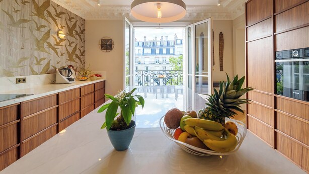A modern kitchen with wooden cabinets, a marble countertop, and a fruit bowl. - Luxery 4Bedroom Apart_Near Arch of Triomphe_With AC & Outbuilding for staff (Paris)