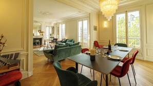 A spacious living area with a dining table set for four, a green sofa, and a chandelier. - Luxery 4Bedroom Apart_Near Arch of Triomphe_With AC & Outbuilding for staff (Paris)
