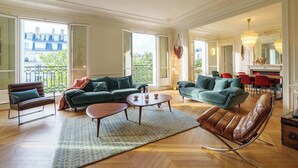 A spacious living room with a large window, a fireplace, and a dining area. - Luxery 4Bedroom Apart_Near Arch of Triomphe_With AC & Outbuilding for staff (Paris)