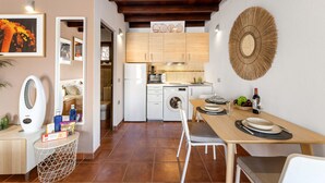 Una cocina compacta con electrodomésticos modernos, un comedor con mesa de madera y un elemento decorativo en la pared.