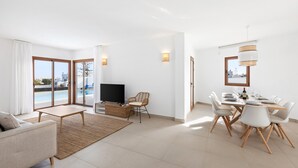 Un salon moderne comprenant un téléviseur, un canapé, une table à manger et des chaises.
