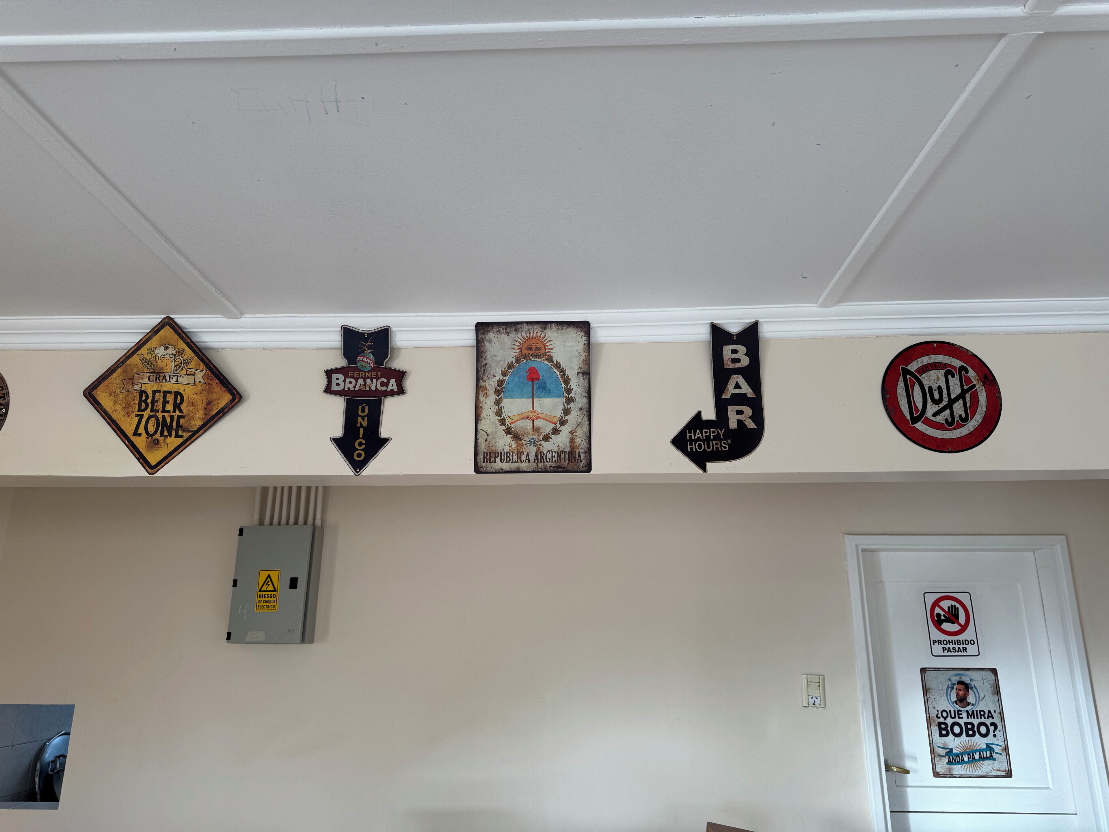 A wall with various signs including a 'Beer Zone' sign, a 'Happy Hours' sign, and a 'Duff' sign.