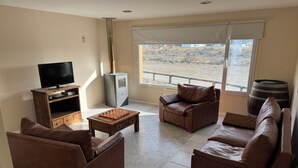 A living room with a sofa, armchairs, a coffee table, a TV, and a fireplace. - Posada Ruta Nacional 40  (Cabo Virgenes)