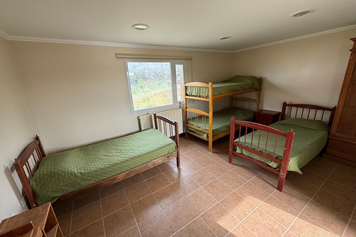 A dormitory room with bunk beds, a window, and a radiator.