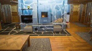 Ein gemütlicher Wohnbereich mit Kamin aus Stein, Holzmöbeln und einem Fernseher.