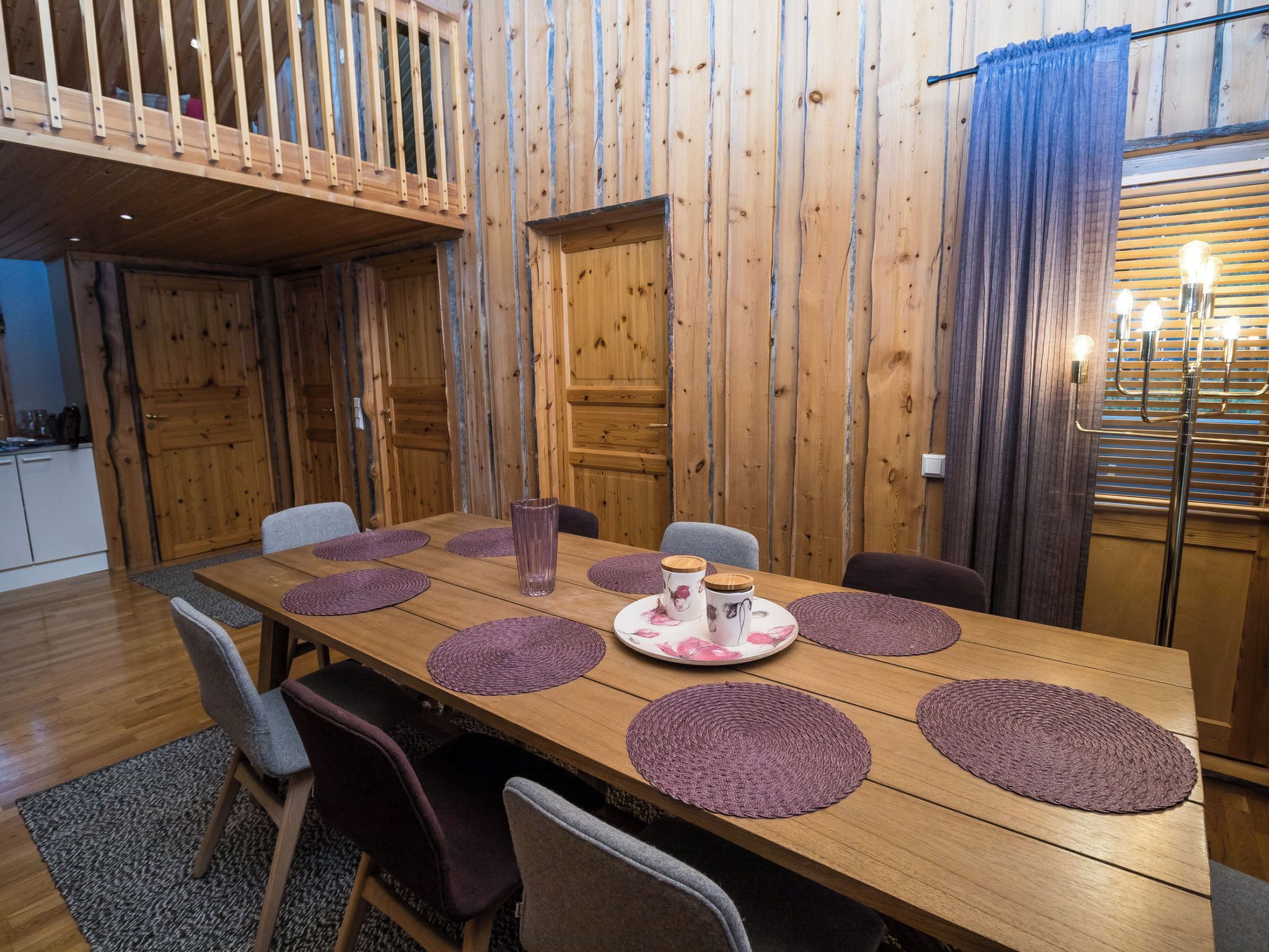 A dining area with a wooden table, purple placemats, and chairs.