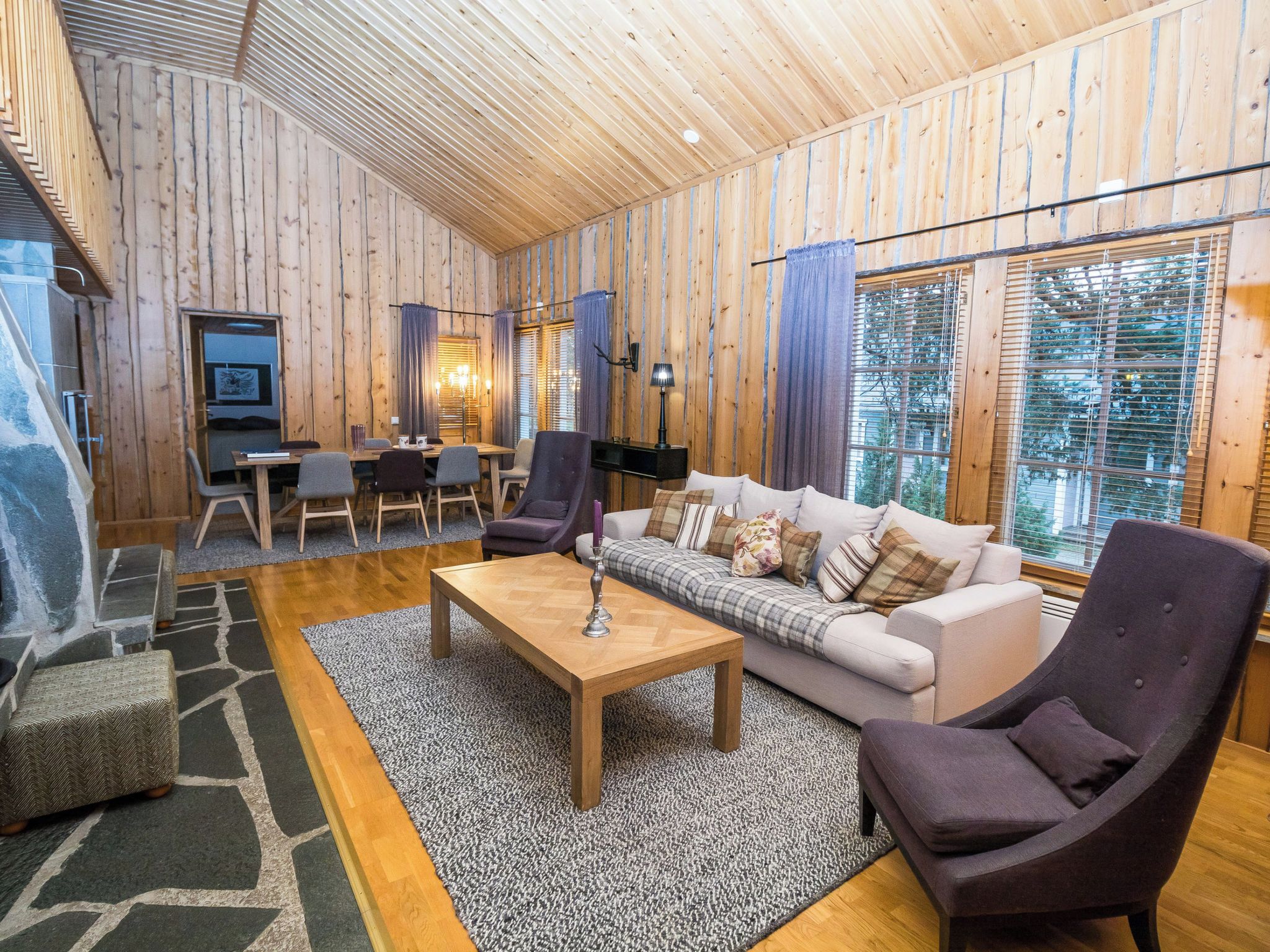 Une pièce chaleureuse avec un plafond en bois, un ensemble de canapés, une table à manger et une cheminée.