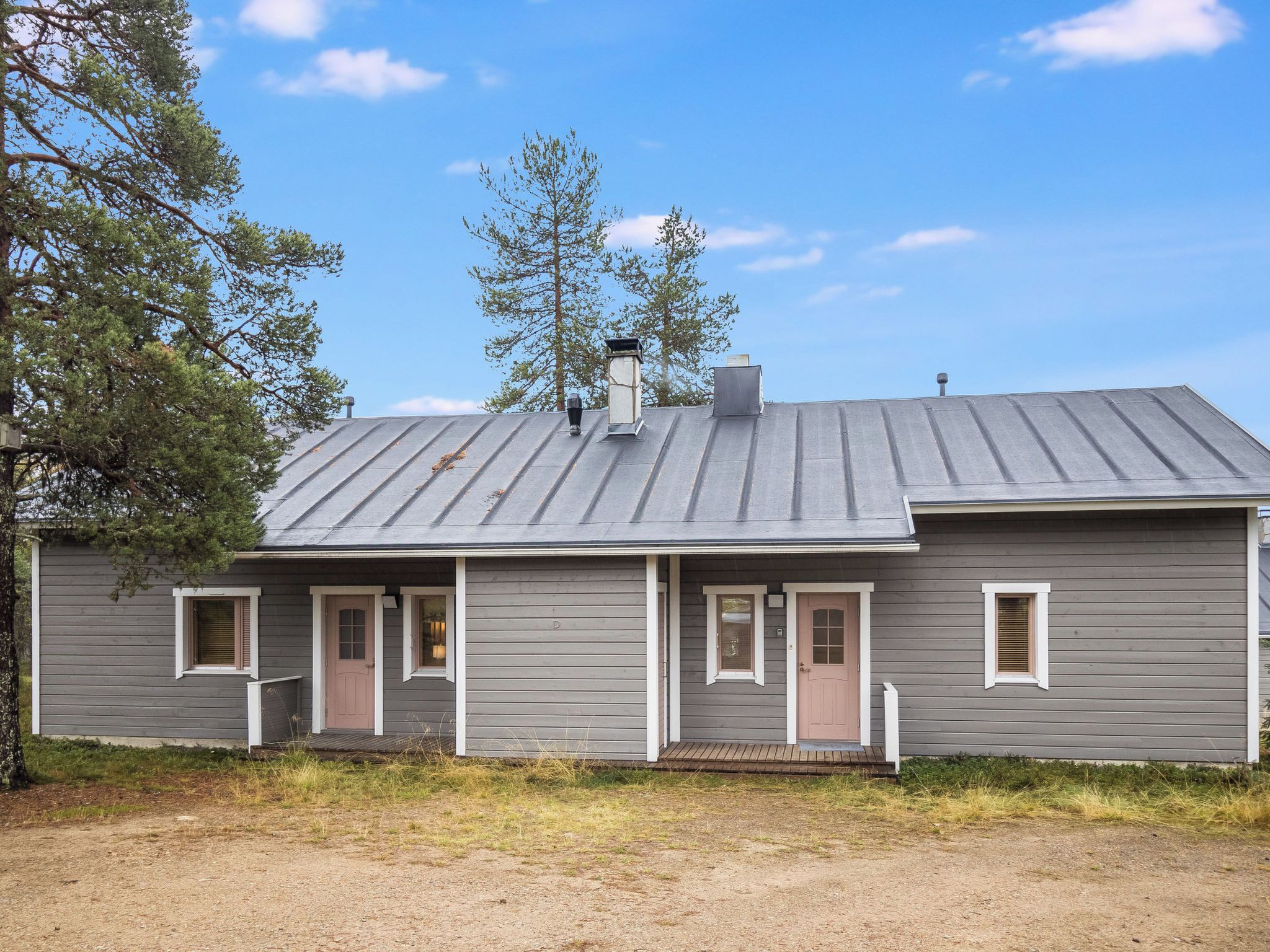 A two-story house with a metal roof, a front porch, and a small front yard.