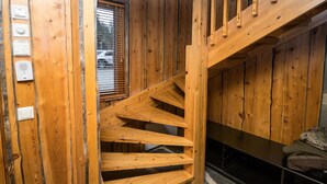 Eine Holztreppe in einer Hütte mit einem Fenster mit Blick auf einen Parkplatz.