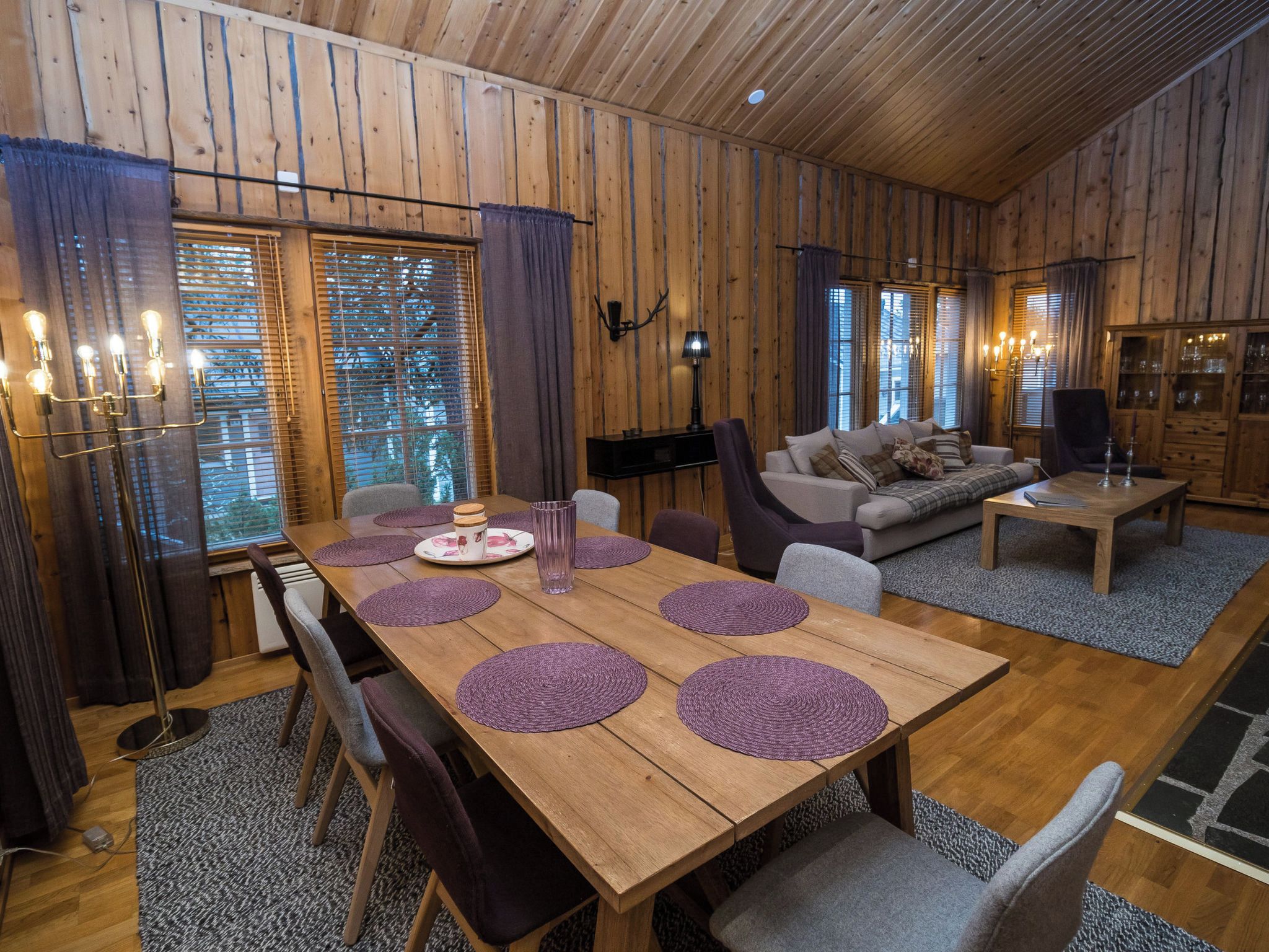 En inredning med träpanel och ett matbord för fyra personer, en soffa och en tv.