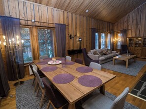 Een houten interieur met een eettafel voor vier personen, een bank en een televisie.