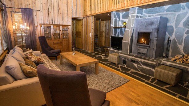 Ein gemütliches Wohnzimmer mit Kamin aus Stein, Holzwänden und einer bequemen Sitzecke.