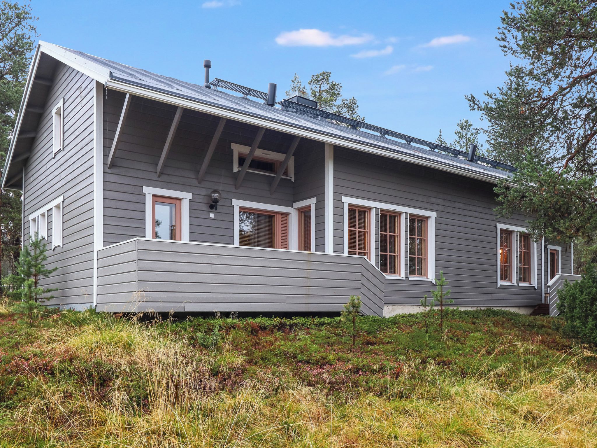 Une maison moderne avec un toit en pente, de grandes fenêtres et une véranda couverte.