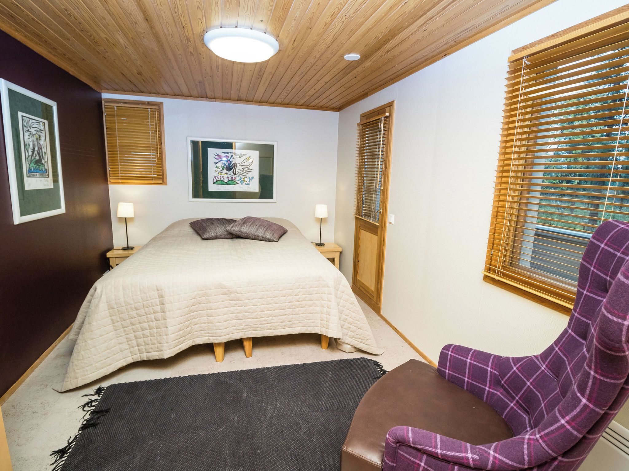 Un dormitorio con una cama, dos lámparas de noche, un cuadro en la pared y una ventana con persianas.