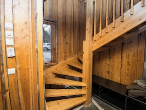 A wooden staircase leading to a second floor, with a window overlooking a parking area.