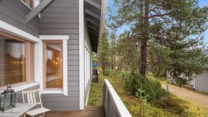 Eine Holzterrasse mit Tisch, Stühlen, einer Laterne und einem Fenster mit Jalousien.