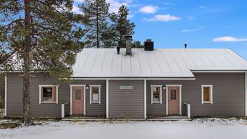 En tvåvåningsbyggnad med ett tak av metall, en skylt med texten ”VILLA KAJO” och en snötäckt mark.