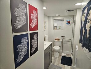 A modern bathroom with a toilet, sink, and shower. There are four framed maps on the wall. - Peaceful, Cozy 2-bedroom apartment in Trinidad with WiFi,  great music. (Trinidad)