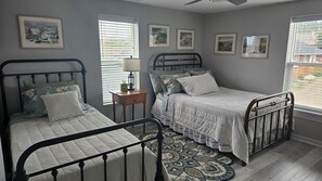 A bedroom with two metal beds, a nightstand, a lamp, and a window with blinds. - Peaceful, Cozy 2-bedroom apartment in Trinidad with WiFi,  great music. (Trinidad)