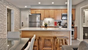 A modern kitchen with wooden cabinets, stainless steel appliances, and a central island with stools.