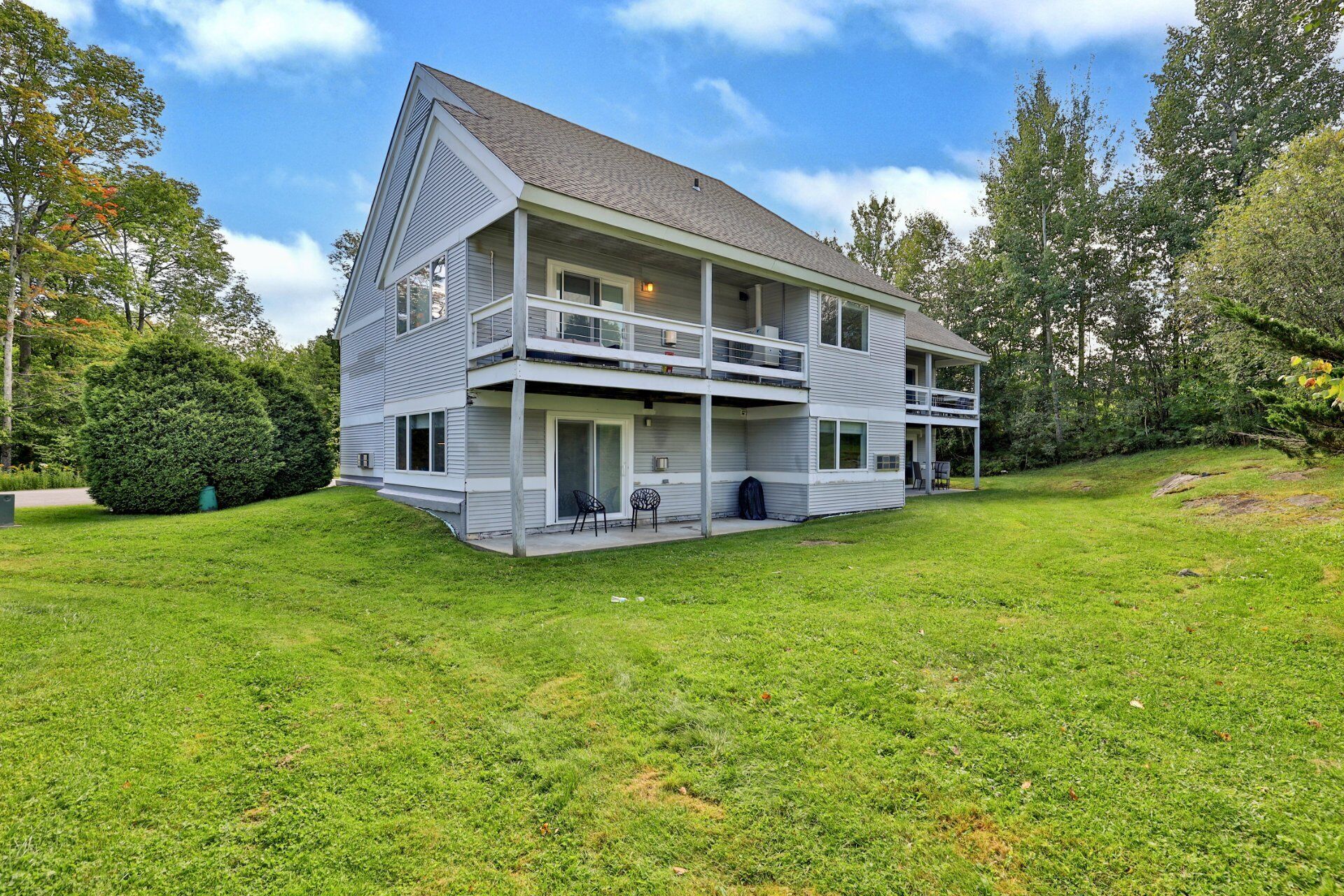 The ground-floor patio opens onto the lawn, with the neighboring condos and trees in view.