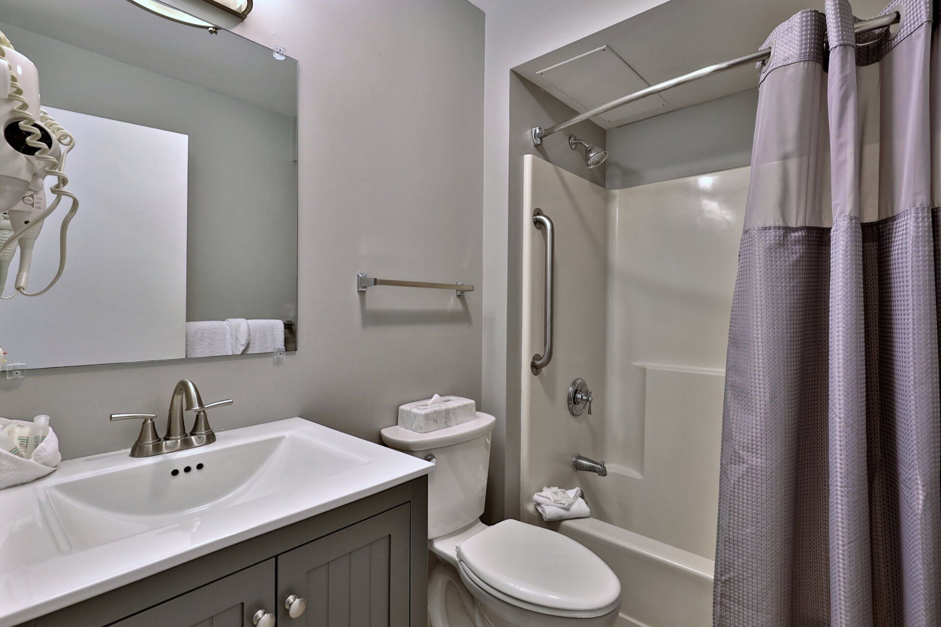 A modern bathroom with a sink, mirror, toilet, and shower.