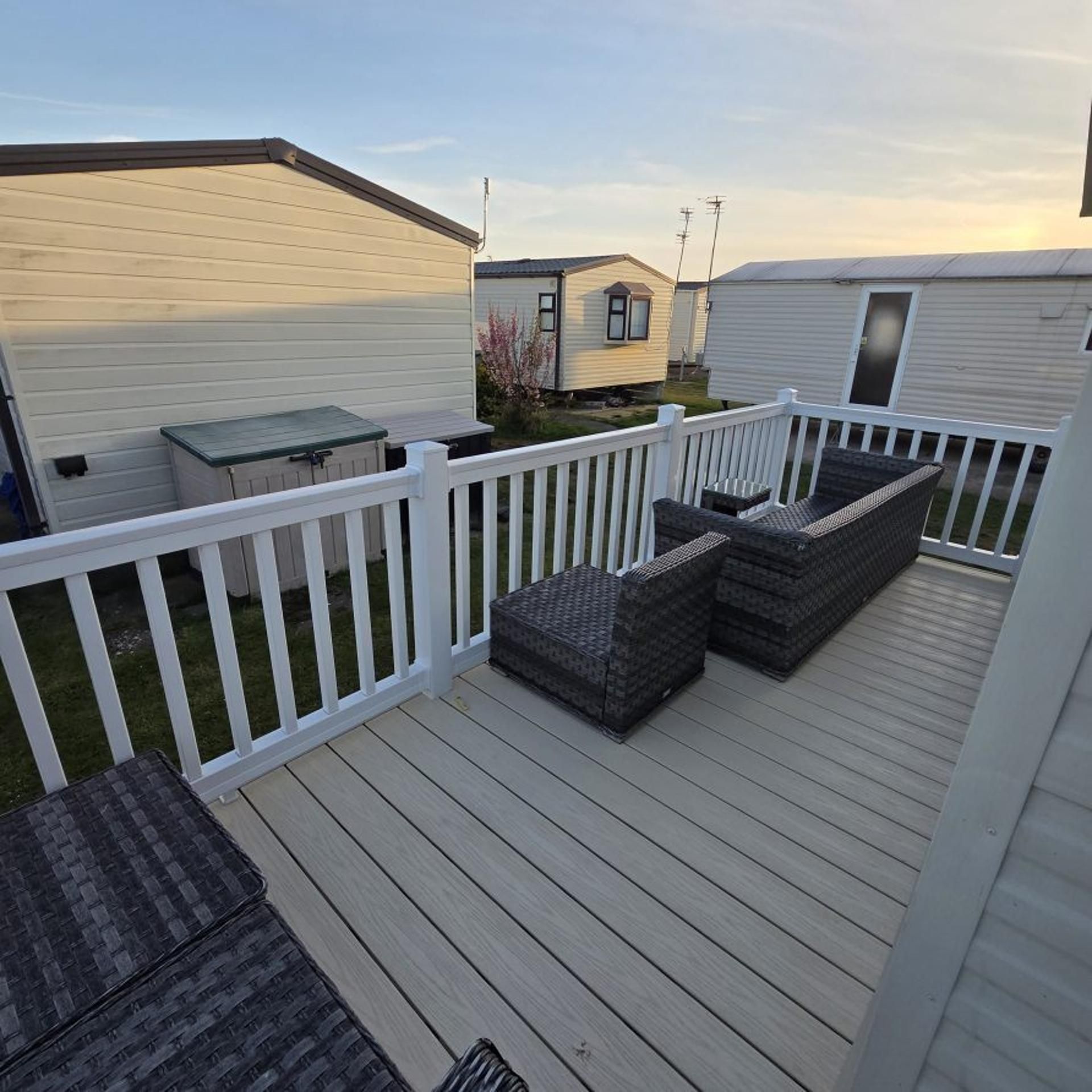 Une terrasse dotée de mobilier d’extérieur et d’une clôture blanche.