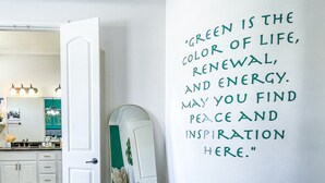 Une pièce avec une porte blanche, un miroir et un mur orné d’une citation inspirante.
