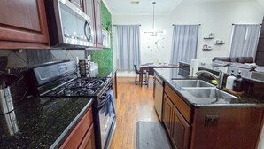 Une cuisine moderne avec des plans de travail sombres, une cuisinière encastrée et un grand îlot central doté d’un évier.