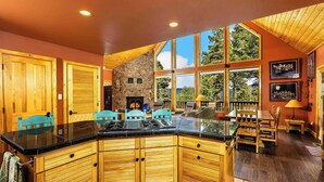 A spacious kitchen with a large island, wooden cabinets, and a stone accent wall. - Spacious Mountain Cabin with Views, Deck, Second Living Area, New Hot Tub (Angel Fire)