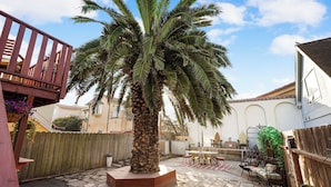 A courtyard with a palm tree, a wooden deck, and a tiled patio. - Coast PalmTree Yard 2BR Block from Beach (Pacifica)
